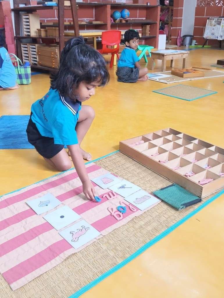 Child focused on Montessori language work mat at Kalpavrikshalaya