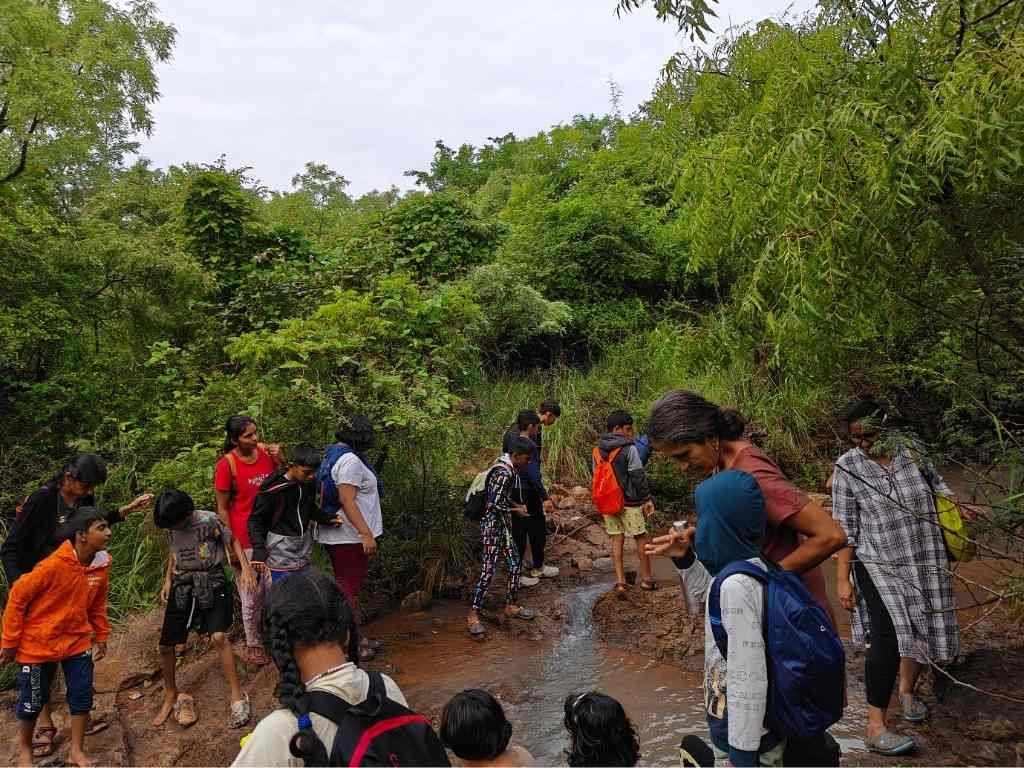 Children and guides exploring natural stream and forest trail on nature excursion